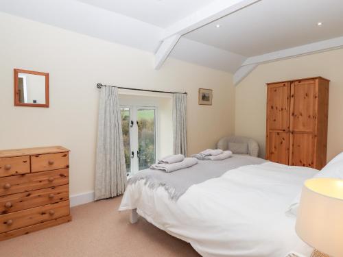 een slaapkamer met een bed, een dressoir en een raam bij Dishcombe Cottage in Okehampton