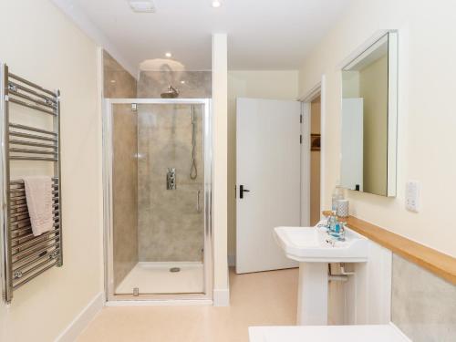 a white bathroom with a shower and a sink at Dishcombe Cottage in Okehampton