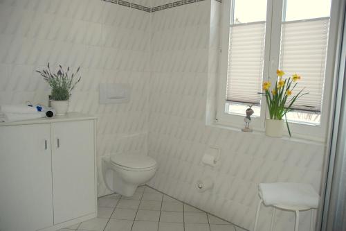 a white bathroom with a toilet and a window at Villa Amanda by Rujana in Binz