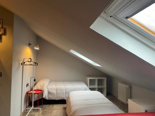 a attic bedroom with two beds and a window at Torre del reloj - Parking gratis in Cazorla