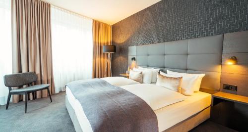 ベルリンにあるビクターズ レジデンツ ホテル ベルリン テーゲルの大きなベッドとデスクが備わるホテルルームです。