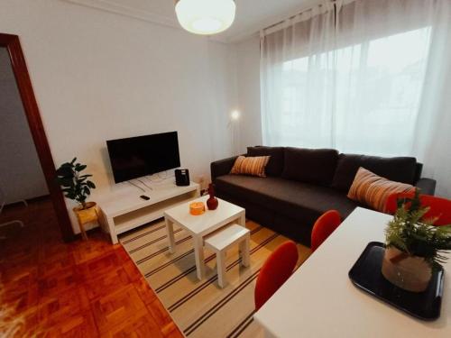 sala de estar con sofá y TV en Apartamento Maura 2 dormitorios, en Oviedo