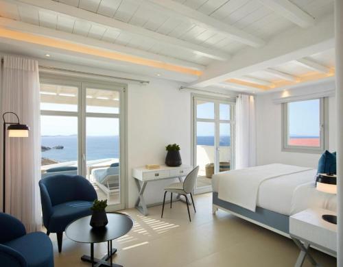 a white bedroom with a bed and a desk and chairs at San Marco Hotel and Villas in Houlakia