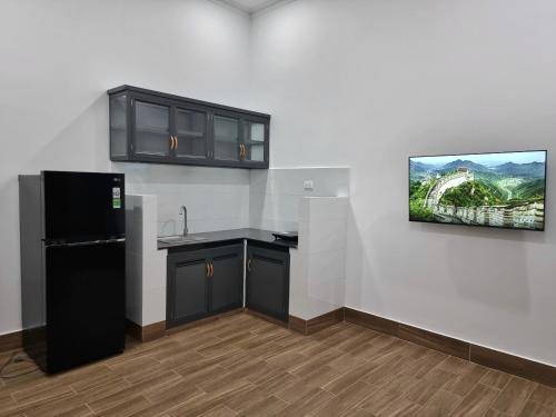 a kitchen with a black refrigerator and a painting on the wall at Cay Phuong Guesthouse in Mui Ne