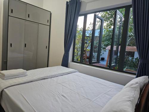 a bedroom with a bed and a large window at Cay Phuong Guesthouse in Mui Ne