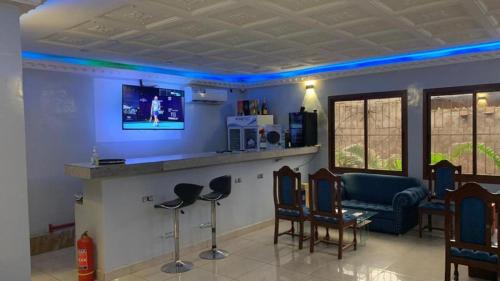a living room with a bar with chairs and a tv at L'Integrale in Yaoundé