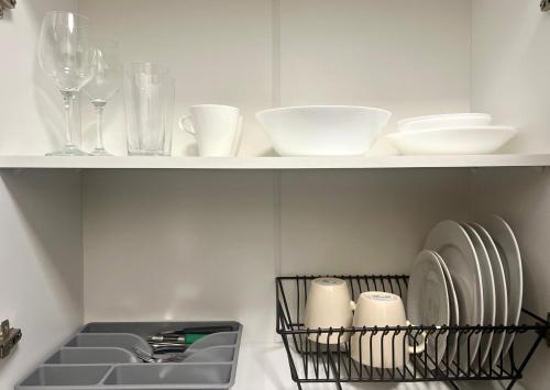 a kitchen shelf with dishes and glasses and a sink at K22 Andersa 12 m Ratusz Arsenał in Warsaw