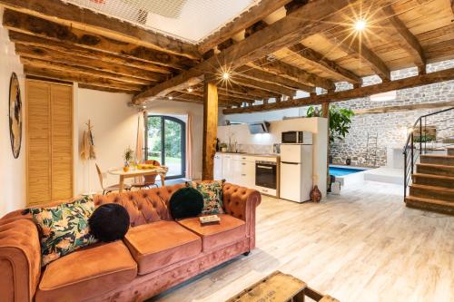 ein Wohnzimmer mit einem braunen Sofa und einer Küche in der Unterkunft Les Hauts de Bagadou in Martel