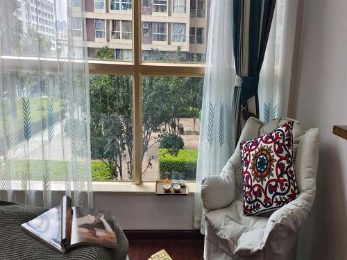 a living room with a chair and a large window at Annie Apartment - only 120 metres from Metro Line 2 Exit B of Chuanxingulou in Kunming