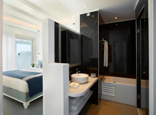 a bedroom with a bed and a sink and a tub at San Marco Hotel and Villas in Houlakia