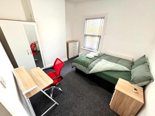 um quarto com uma cama e uma cadeira vermelha em Three Rose Manor At Warwick Road Near Birmingham Airport em Birmingham