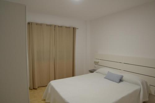 1 dormitorio con cama blanca y almohada azul en LEOAN,sL, en Los Llanos de Aridane