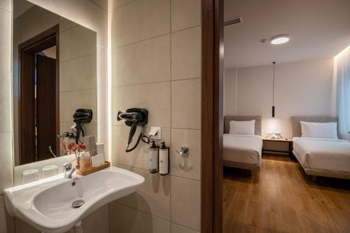 a bathroom with a sink and a mirror and a bedroom at IRA - ΗΡΑ Hotel in Kalamata
