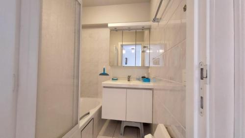 een witte badkamer met een wastafel en een douche bij Zeedijk Koksijde in Koksijde