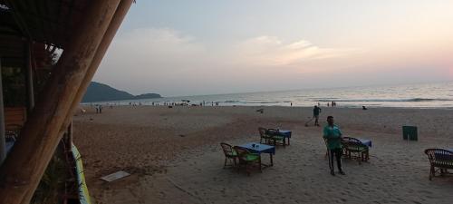 a woman standing on a beach with tables and chairs at SAI HOMESTAY in Agonda