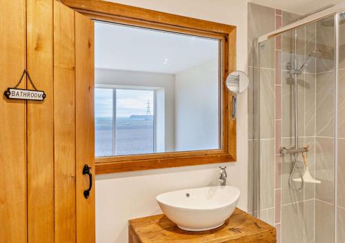 a bathroom with a sink and a mirror and a window at Abbots Barn in Upwell