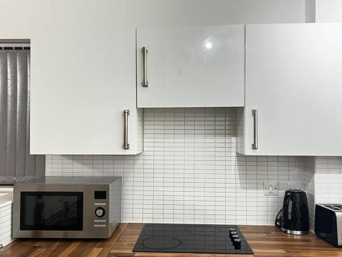a kitchen with white cabinets and a microwave at Relax in this cosy Haven near Glenfield and Royal Infirmary Hospitals in Leicester