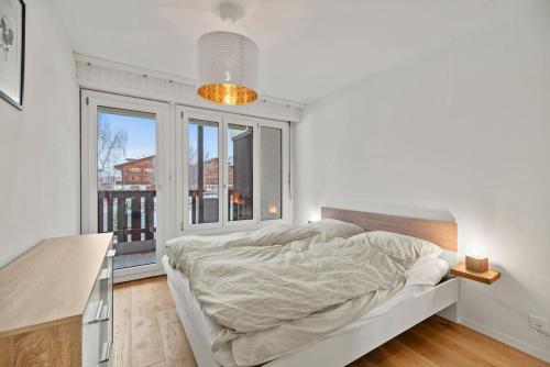 a white bedroom with a bed and a window at Appartement calme et accueillant à Charmey in Charmey