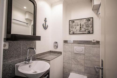 un bagno bianco con lavandino e specchio di Kompass Sylt a Westerland