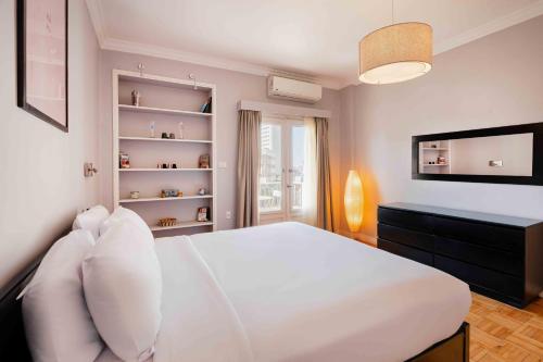 1 dormitorio con 1 cama blanca grande y TV en Brassbell l Cozy 1 BR apartment in Zamalek en El Cairo