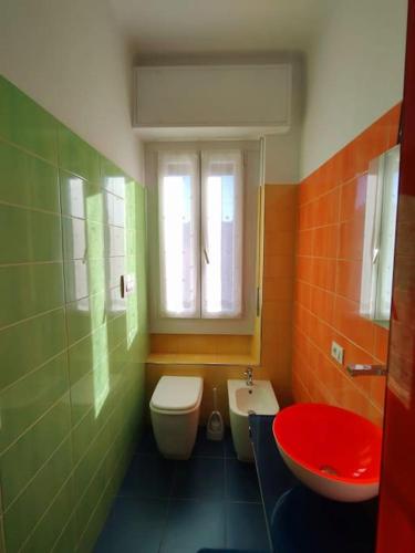 a green and orange bathroom with a toilet and a sink at Bilocale luminoso e accogliente zona Marche in Milan