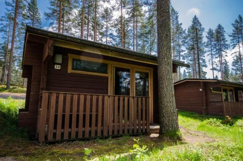 una pequeña cabaña en el bosque junto a un árbol en Ahvenlampi Camping Hostel, en Saarijärvi