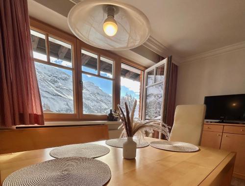 Hillside One - Ski-In Ski-Out Apartments am Arlberg في وارث ام ارلبرغ: طاولة غرفة الطعام مطلة على الجبال المغطاة بالثلوج