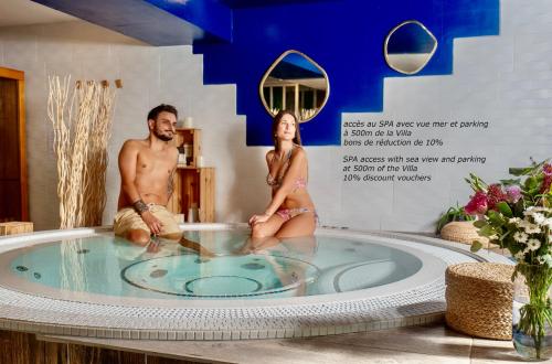 Un uomo e una donna seduti in una vasca idromassaggio di Blue Summer Vibes Apartment for 4P, AC, parking, beach at 50m, SPA access -1 a La Ciotat