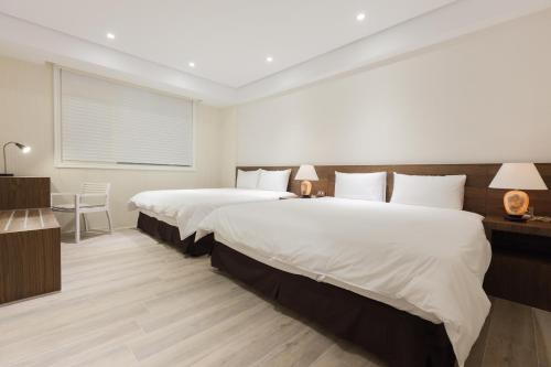 a bedroom with two beds and a table with lamps at Lanven Art House in Hualien City