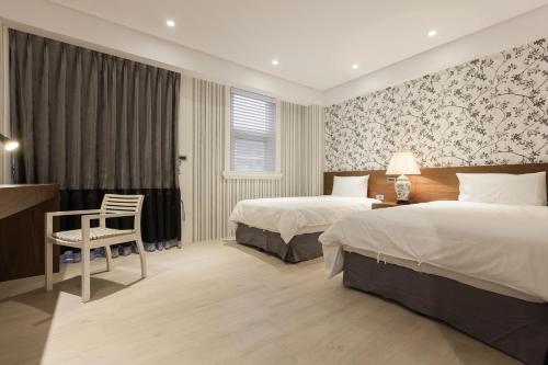 a hotel room with two beds and a chair at Lanven Art House in Hualien City