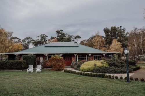 a house with two white chairs in front of it at Green Gables B&B Waterfront Apartment with King Bed & Breakfast in Huon Valley in Cygnet