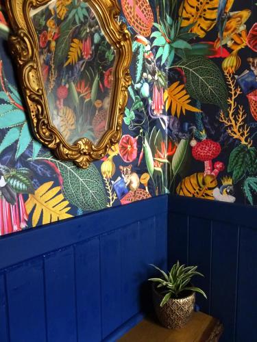 a blue wall with a mirror and a potted plant at Havana House - Luxury Property Near Harbour in Weymouth