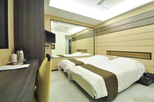 a bedroom with two beds and a large mirror at Hotel Esteem in Kolkata