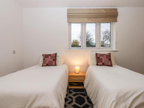 two twin beds in a room with a window at The Linhay in Crediton