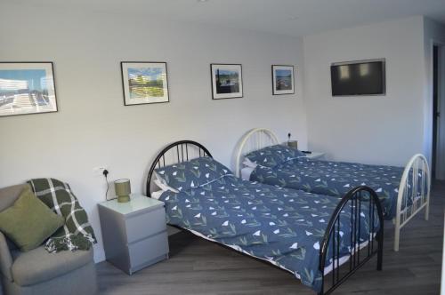 a bedroom with two beds and a chair at Greenfield Studio in Cardiff