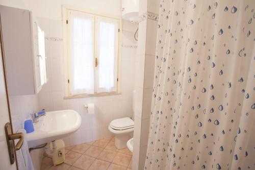 a bathroom with a shower curtain with a toilet and a sink at Appartamenti Villa Anna - Goelba in Capoliveri