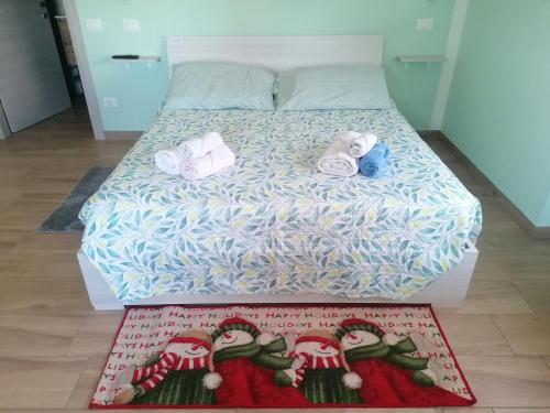 a bed with towels on it with a rug on the floor at Colori nel Parco 2 in Cesiomaggiore