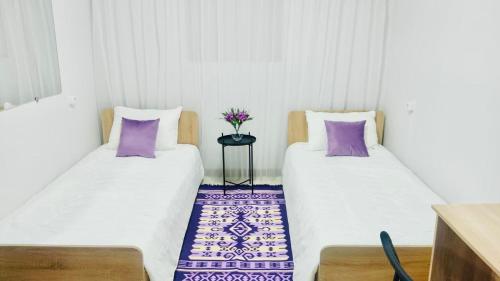 - 2 lits dans une petite chambre avec des oreillers violets dans l'établissement Like Home Hostel na Timiryazeva, à Almaty