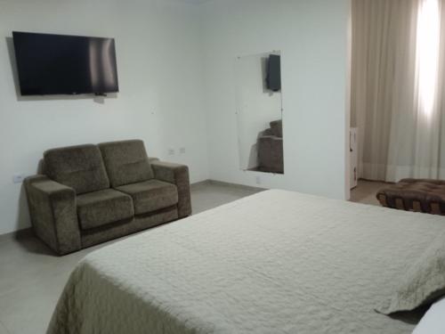 Colinas do Tocantins的住宿－Hotel Villa do Sol，一间卧室配有一张床、一把椅子和电视