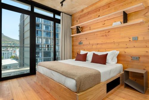 1 dormitorio con 1 cama con pared de madera en Neighbourgood 84 Harrington, en Ciudad del Cabo