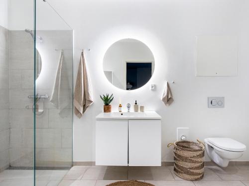 La salle de bains blanche est pourvue d'un lavabo et d'un miroir. dans l'établissement Sanders Leaves - Chic Three-Bedroom Apartment In Downtown Copenhagen, à Copenhague