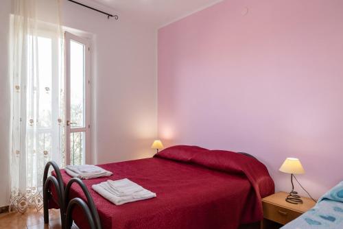 a bedroom with a red bed and a window at Casa Bianca in Licata