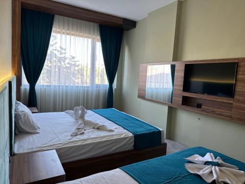 a hotel room with two beds and a flat screen tv at Kançul Hotel Taştepeler in Sanlıurfa