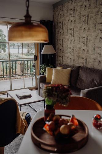 CygnetにあるGreen Gables B&B Waterfront Apartment with King Bed & Breakfast in Huon Valleyのリビングルーム(フルーツプレート付きのテーブル付)