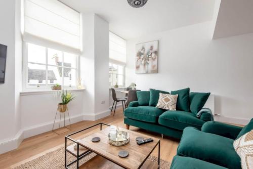 a living room with a green couch and a table at Skye Sands - Old Course Residence in St. Andrews