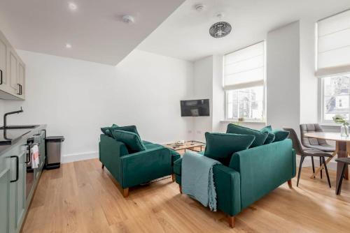 a living room with green chairs and a table at Skye Sands - Old Course Residence in St. Andrews