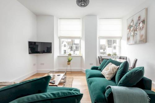 a living room with green couches and a tv at Skye Sands - Old Course Residence in St. Andrews