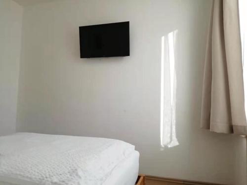 a bedroom with a bed and a television on a wall at Hotel Hanseatic-garni in Wuppertal