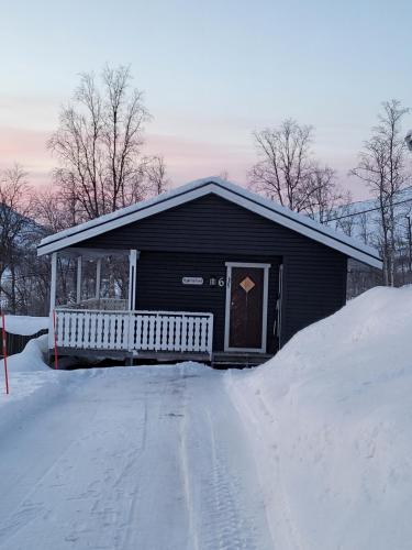 a black house with a porch in the snow at Lapphaugen Turiststasjon in Tennevoll