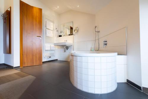 a bathroom with a white tub and a sink at Hotel Darstein in Mannheim